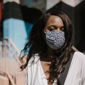 A woman wearing a face mask in front of a wall.