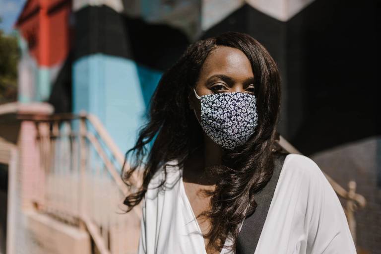 A woman wearing a face mask in front of a wall.